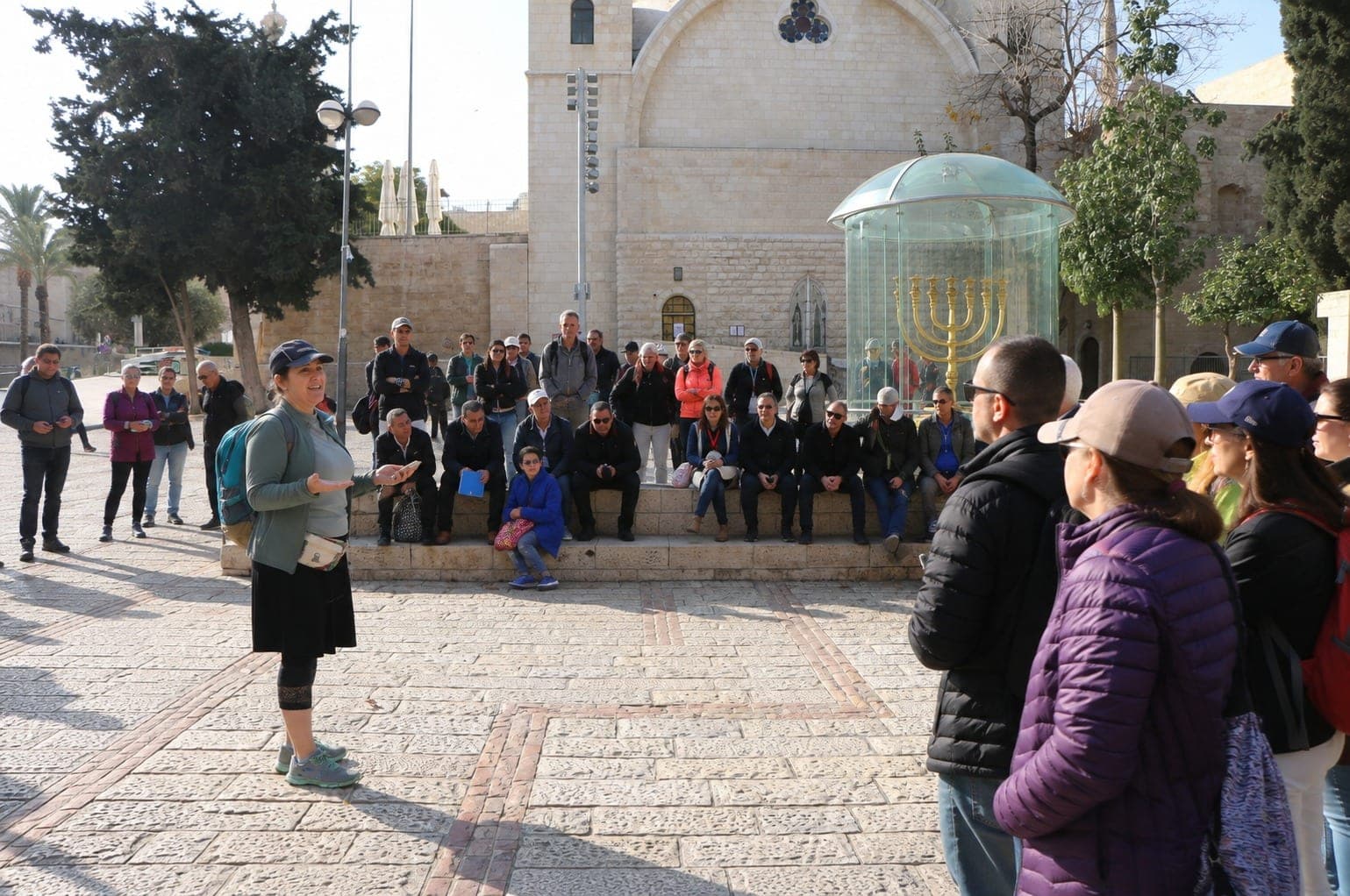 הדרכת קבוצה בסיור בירושלים, ברקע המנורה בכיכר החורבה